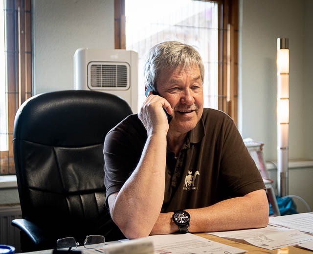 Tom Bode telefonierend am Schreibtisch sitzend